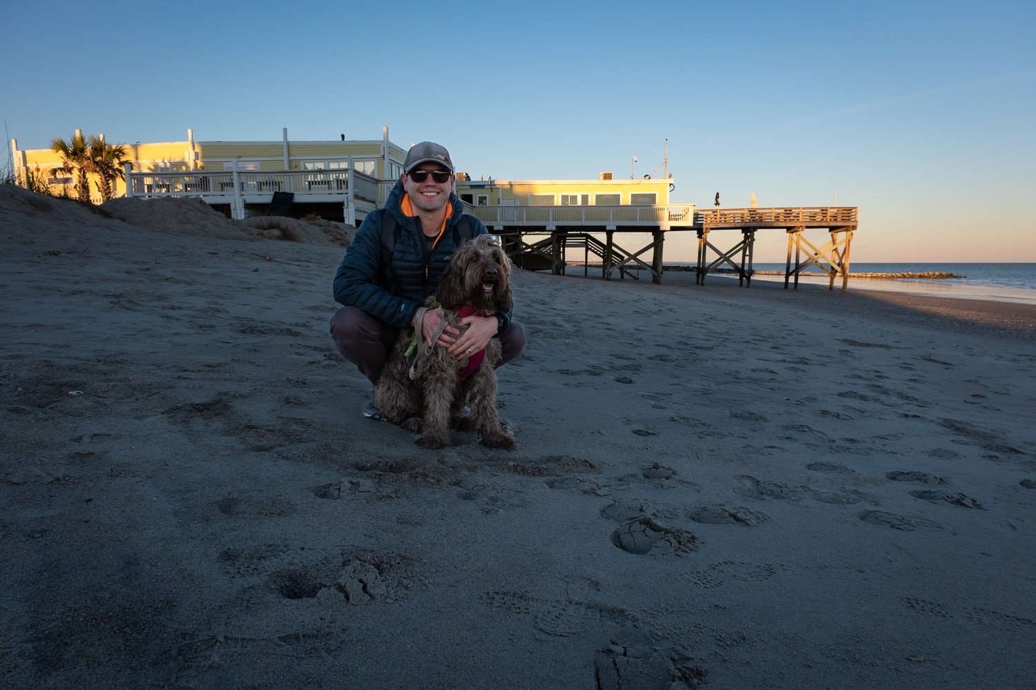 Male and his dog smiling in front of a local waterfront dining option in Edisto Beach South Carolina 